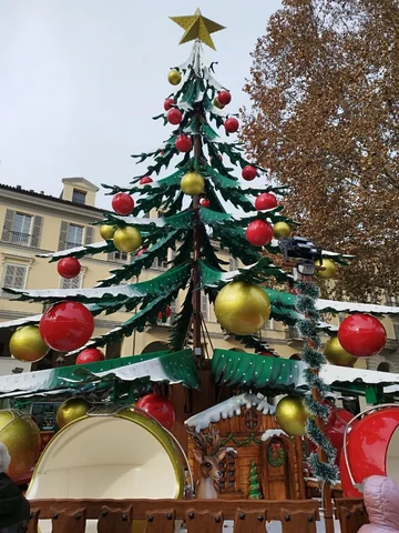 Christmas tree ride operating in a city street, with gift-shaped cabins around the base