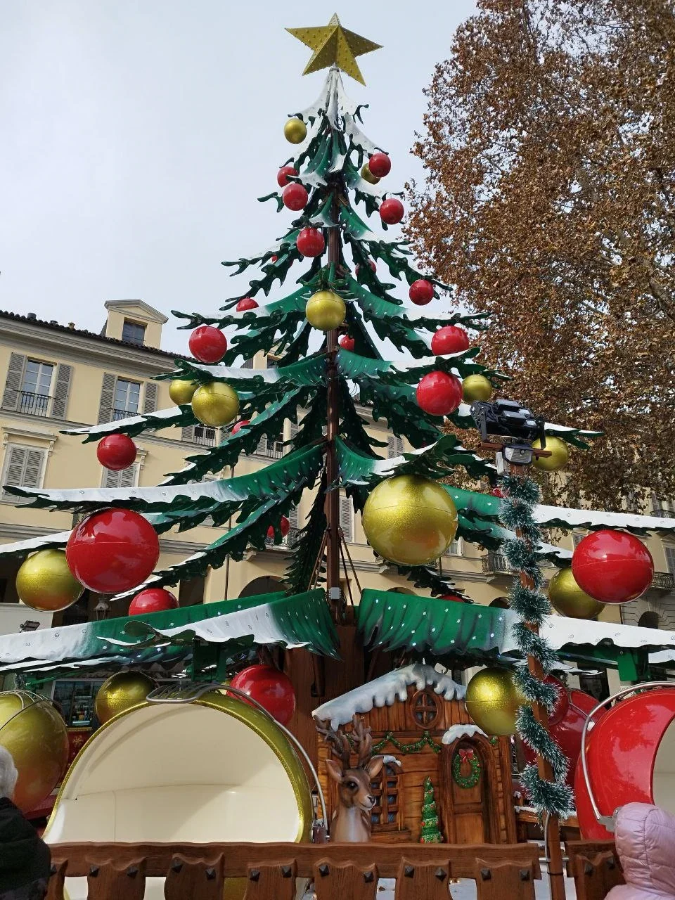 Christmas tree ride operating in a city street, with gift-shaped cabins around the base